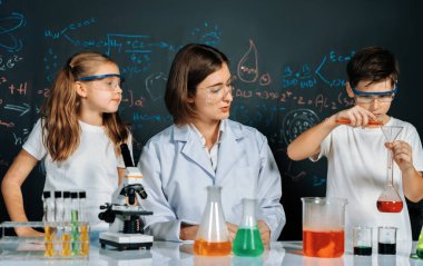 Laboratuvarda çalışan öğretmen, güvenlik gözlüğü takıyor, STEM sınıfında kimya bilimi üzerine deney yapıyor. Öğrenci komedisi tüpte sıvı deneyi yapar. Etkinlik.