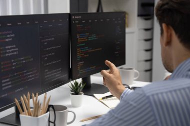 Bilgi teknolojisi geliştiricisi, bilgisayar ekranına bilgi doğrultuyor, program güncellemesi analizi yapıyor ve modern ofiste ilginç bir web sayfası verisi yaratıyor. Varsayım.