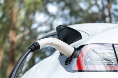 Kapalı EV şarj kolu fişe takıldı veya elektrikli arabaya bağlandı, EV araba aküsünü temiz çevre için sıfır CO2 emisyonu ile alternatif ve sürdürülebilir enerjiyle şarj etti. Kalıcı