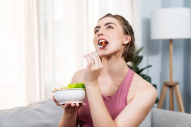 Spor giyimli sağlıklı ve vejetaryen bir kadın bir kase meyve ve sebzeyle. Sağlıklı beslenme ve spor için vejetaryen yaşam tarzı ev konseptinde vücut fiziği.