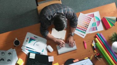 Akıllı iş adamının logo grafiği tasarlarken renk paletleri seçmesinin üst görünümü. Profesyonel iç mimar tasarımının hava görünümü ve renk paletleri kullanarak renk temasını seçin. Sempozyum.