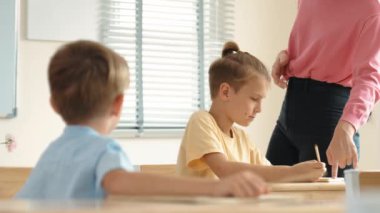 Beyaz bir çocuk ödevlerini yaparken ve açıklama dinlerken güzel bir öğretmen sınavı açıklıyor. Sınıfta not alırken ya da kağıda cevap yazarken öğretmenine bakan sevimli bir çocuk. Pedagoji.