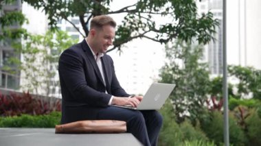 Dizüstü bilgisayarı üzerinde çalışan ve başarılı bir projeyi kutlayan ya da yeşil kentlerdeki satışları artıran bir yönetici. Profesyonel işadamı bankta otururken bilgisayar kullanarak analiz verilerine bakıyor. Urbane.