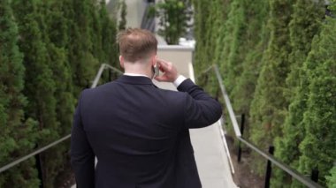 Mutlu iş adamı merdivenlerden inip akıllı telefon kullanarak müdürü arıyor. Becerikli bir yöneticinin eve dönmek için merdivenlerden inerken telefonla pazarlama ekibini konuşması. Urbane.