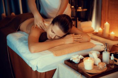 Beyaz kadın müşteri stres önleyici spa masajının keyfini çıkarıyor ve lüks otel ya da otelde sıcak mum ışığında güzellik teniyle eğleniyor. Sessiz.