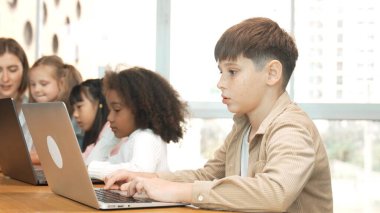 Çocuk BTMM Teknoloji sınıfında çok kültürlü bir arkadaşla bilgisayar oyunu oynuyor. Mühendislik kodları ve bulanık geçmişi olan programlama sistemi üzerine çok kültürlü bir öğrenci çalışması. Etkinlik.