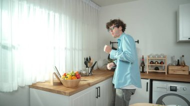 Mutlu baba yemek pişirirken müziğe geçiyor ve modern mutfakta öğle yemeği hazırlıyor. Aktif baba, sebze ve mutfak gereçleri ile çevrili sağlıklı yemek ya da salata yaparken şarkıyla dans ediyor. Pedagoji.