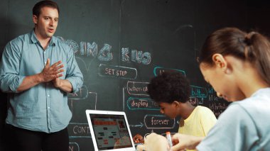 Kafkas öğretmeni alkışlayarak öğrencileri kodlamayı veya programlamayı teşvik etmek için alkışlıyor. Çeşitli öğrenciler STEM sınıfına katılırken başarılı bir projeyi kutlamak için el çırpıyorlar. Öğretim.