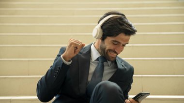 Kulaklık takarken müzik dinleyen ve eğlenen zeki iş adamlarına yakın çekim. Proje yöneticisi gülümserken iyi haberler alıyor, terfi alıyor, satışları artırıyor. Rahatlatıcı adam müzikten hoşlanır. Sevinçli..