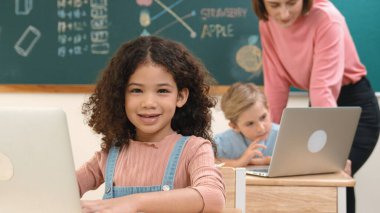 Çekici kız kodlama hızlı BTMM sınıfında kameraya bakarken mutlu öğretmen akıllı çocuk yazılım programını kontrol ediyor. Programlama kodu ve bilgisayar sistemi üzerine çeşitli öğrenci çalışmaları. Pedagoji.