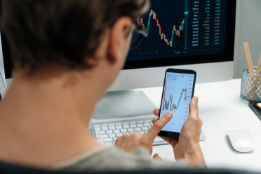 Akıllı borsa yatırımcıları ekranda akıllı telefon ile piyasa borsasını işaret ederek dizüstü bilgisayarın yanı sıra en yüksek dinamik yatırım oranını göstererek, modern işyerindeki veri planlamasına odaklanıyorlar. Bireysel.