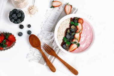 Meyvelerin sunduğu yoğurt malzemelerini çilek, yulaf, kuru üzüm ve nane şekeriyle süslenmiş Chia tohumu ile beyaza boyarız. Pembe arka plan. Sağlıklı süt ürünleri seti. Bireysel.