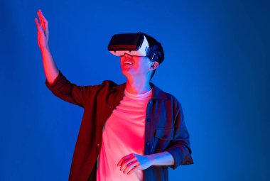 VR gözlüklerinden bakan zeki Asyalı adam, yenilikçi teknolojide dokunmatik ekran ile 3D hologram meta arayüzünü analiz ederek metazıt doğrultuda araştırma dizini verilerine dönüyor. Entrika.