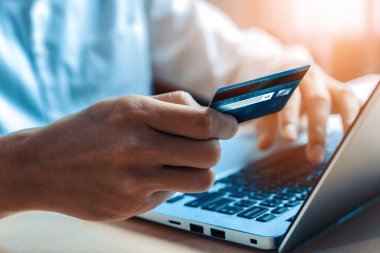 Genç adam, laptop bilgisayar başvurusu ya da web sitesinde online alışveriş yapmak için kredi kartı kullanıyor. E-ticaret ve online alışveriş konsepti. uds