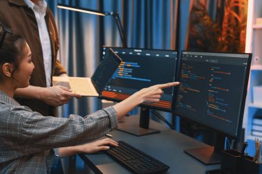 Modern ofisteki neon ışık odasında bilgi ağını gösteren dizüstü bilgisayarla iki ekranda veri çalıştıran akıllı web sitesi geliştirme kodlayıcı sistemini tartışan IT geliştiricilerinin ciddiyeti. İnfobahn.