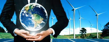 Alternatif enerji ile sürdürülebilirlik gelişimi kavramı. Çevre dostu rüzgar türbini çiftliği ve arka planda yeşil yenilenebilir enerji olan gezegenle insan eli ilgilenir. uds