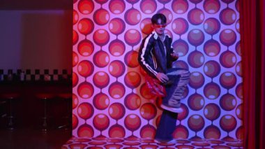 Asyalı break dansçı serbest stile geçiyor ve balon arka planlı kameraya bakıyor. Profesyonel hippi gündelik kıyafet giyer ve gözlük takar. Mutluluk.