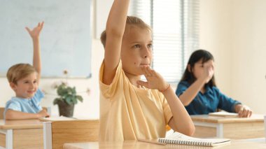 Ciddi öğrenci sınıfta otururken soruyu cevaplamak için elini kaldırdı. Sınıfta birlikte çalışırken günlük giysiler içindeki çok kültürlü çocuklar derse katılıyorlar. Çok basit. Pedagoji.