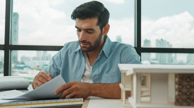 Kafkas mimari mühendisinin portresi planda gayrimenkul tasarımı yapıyor. Ev modeli inşaatına bakarken profesyonel bir mühendis taslak çiziyor. İnşaat mühendisliği konsepti. İzleme