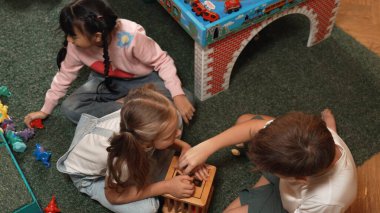 Anaokulunun oyun odasında ahşap blok oynayan çok kültürlü ve zeki öğrencilerin en iyi görüntüsü. Çeşitli çocuklar yaratıcılığı ve hayali geliştirmek için oyuncak oynarlar. Yaratıcı aktivite konsepti. Etkinlik.