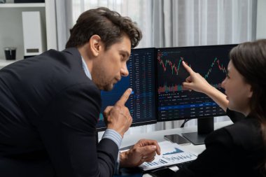 Dinamik borsada döviz kuru yatırımını tartışan iki ticaret simsarı iki bilgisayar ekranında gerçek zamanlı risk grafiği ya da modern ofisteki kar noktasını karşılaştırıyor. Varsayım.