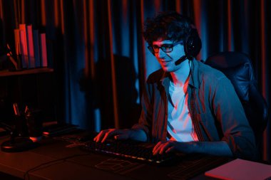 PC dövüş oyununda Esport 'ta oyun çubuğuyla oynayan gülümseyen genç oyun flaması takımı, kırmızı neon ışıklı modern odada gelecek için strateji planlamasında rakiplerini kazanmaya çalışıyor. Toplayıcı.