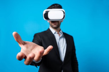 Profesyonel, zeki iş adamı, VR gözlük takarken elinde bir şey tutuyor. Sanal gerçeklik gözlüklü Kafkas proje yöneticisi mavi arka planlı mevcut teknoloji yeniliği. Sapma.