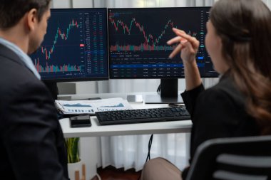 Dinamik borsada döviz kuru yatırımını tartışan iki ticaret simsarı iki bilgisayar ekranında gerçek zamanlı risk grafiği ya da modern ofisteki kar noktasını karşılaştırıyor. Varsayım.