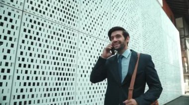 Akıllı iş adamı iş yatırımları hakkında konuşmak için telefonu kullanıyor. İş planı, pazarlama stratejisi ya da çalışma hakkında konuşmak için akıllı telefonla konuşurken sokakta yürüyen mutlu bir yönetici. Sevinçli..