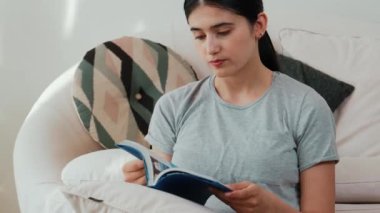 Kanepede oturan orta yaşlı bir kadın, sosyal ve teknolojik mesleki gelişmeler hakkında ders kitabı okur ya da zeki bir anne olmak için çocuk yetiştirir. Hayat boyu öğrenme konsepti. Uyumsuzluk.