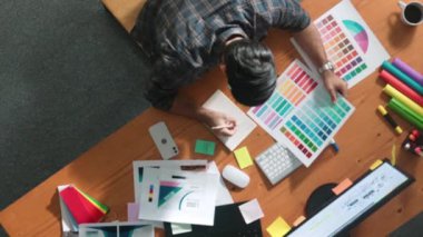 Kulaklıktan müzik dinlerken yetenekli iç dizayn grafiklerinin yukarıdan aşağı havadan görüntüsü. Proje yöneticisi kulaklıkla çalışırken ve rahat şarkılar dinlerken stüdyoda hareket ediyor. Sempozyum.