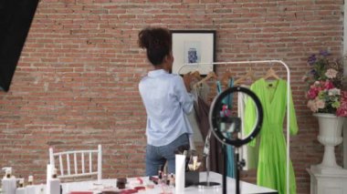 Kadın nüfuzlu kişi canlı yayında video görüntülerini çekiyor. Kıyafetler sosyal medya ya da blog için çok önemli. Stüdyo ışıklandırmalı mutlu genç kız çevrimiçi pazarlama oturumu yayını için..