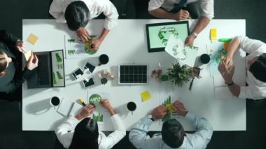 İş adamlarının rüzgar değirmeniyle toplantı masasında temiz enerji ve sürdürülebilir yatırım kullanımı, çevre grafiği ve ahşap ev modeli ile ilgili tartışmalarına tepeden aşağı bakış açısı. Hizalama.