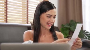 Mutlu bir kadın, faturalarını internet üzerinden öderken gülümseyerek kanepede oturur, tüm faturaları tek seferde ödemenin rahatlığını taktir eder ve kredi kartının sunduğu ödülün tadını çıkarır. Blithe