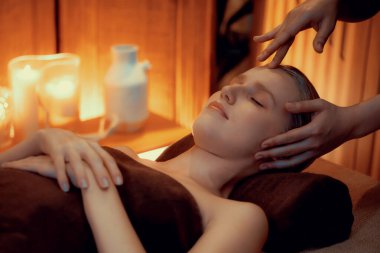 Beyaz kadın stres önleyici kafa masajı yapmaktan ve lüks otel veya otelde sıcak mum ışığında yüz güzelliği eğlencesi yapmaktan zevk alıyor. Sessiz.