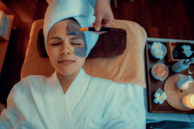 Kaplıca salonunun sakin atmosferi, üst düzey kadın müşteri sıcak mum ışığında kömür kömürü yüz kremi masajıyla kendini yenilemeye çalışıyor. Yüz bakımı ve güzellik konsepti. Sessiz.