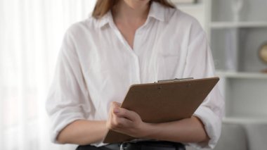 Psikiyatri ofisinde ya da terapi odasında kol koltuğunda oturan profesyonel bir kadın psikolog. Arkadaş canlısı ve ilkel ruh sağlığı danışmanı ve terapisti.