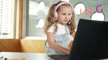 Dizüstü bilgisayarda çalışan ya da online sınıfta okuyan genç bir öğrenci. Ev ödevi yaparken ya da müzik dinlerken bilgisayarda yazan beyaz bir kız. Kulaklık takan küçük bir çocuk. Yaratıcı öğrenme. Etkinlik.