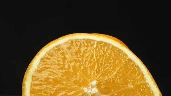 stock image A macrography capture of an orange slice, placed against a sleek, isolated black backdrop, unfolds as a visual masterpiece of citrus allure. A slice of orange with black background. Comestible.