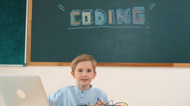 Kameraya karatahta ile bakarken elektronik tahtada çalışan zeki bir öğrenci. Çocuk, kodlama mühendisliği ve yapay zeka kullanarak programlama sistemine hazırlanırken ana tahtayı tamir ediyor. Pedagoji.