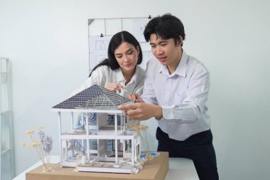 Kooperatif mühendis ekibinin portresi ev modelini ölçmek için cetvel ve mimari ekipmanlar kullanarak birlikte çalışıyor. Yaratıcı iş tasarımı ve takım çalışması konsepti. Tertemiz...