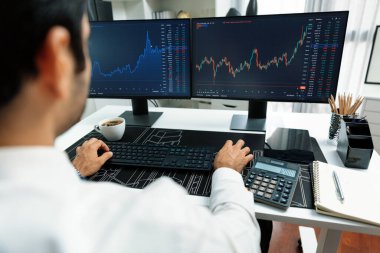 Akıllı tüccar işadamı, modern merkez ofisindeki araştırma pazarında en yüksek kârlı finansal teknolojiye yatırım yaparak bilgisayar üzerinde iki dinamik borsa yatırım ekranını analiz ediyor. Tahmin et..