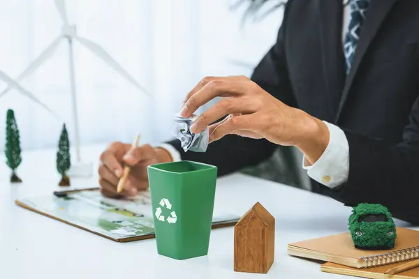 stock image Businessman put paper waste on small tiny recycle bin in his office symbolize corporate effort on eco-friendly waste management by recycling for greener environment and zero pollution. Gyre