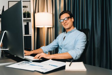 Akıllı iş adamı iş paragrafı dinamik pazarlama analizi planını analiz ediyor. Kağıt kağıtları ve bilgisayar monitörü raporlarını gece evdeki belge verileriyle karşılaştırmak için hazırlıyor. Bireysel.