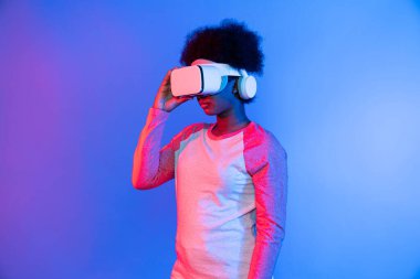 Profil, VR gözlük takan genç ve güzel Afrikalıların mavi ve pembe neon ışıklı arkaplanda izole olduğunu düşünüyor. Teknoloji ve dijital yenilik 3 boyutlu hologram gramında. Entrika.