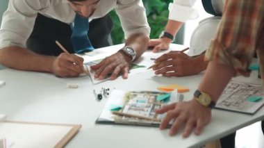 Akıllı iş adamlarının tasarımı planlamak için tabletten proje planına bakarken ve planlar ve toplantı masasındaki bina inşaatı hakkında tartışırken birlikte çalışması. Hizalama.