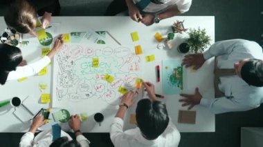 Profesyonel iş adamlarının zihin haritasını kullanarak beyin fırtınası yapmak için birlikte çalıştıklarına dair üst düzey bir görüş. Akıllı yöneticilerin sürdürülebilir enerji hakkında konuştuğu ve tartıştığı hava görüntüsü. Hizalama.