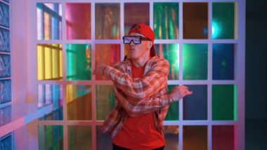 Serbest stil tişört giyerken sokak müziği çalan mutlu hipster. Gece kulübünde neon ışıkla dururken çekici break dansçı dans ve hareketli hareketler yapıyor. Mutluluk.