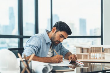 Kafkas mimari mühendisinin portresi planda gayrimenkul tasarımı yapıyor. Ev modeli inşaatına bakarken profesyonel bir mühendis taslak çiziyor. İnşaat mühendisliği konsepti. İzleme