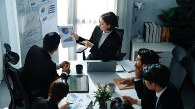 Akıllı yöneticinin üst görünümü, kurul ve kağıt arasındaki grafiği karşılaştırırken aynı zamanda başlangıç projesini iş toplantısında çeşitli takımlardan oluşan bir grupla birlikte planlıyor. Beyin fırtınası yapan ve birlikte çalışan takım. Müdürlük.
